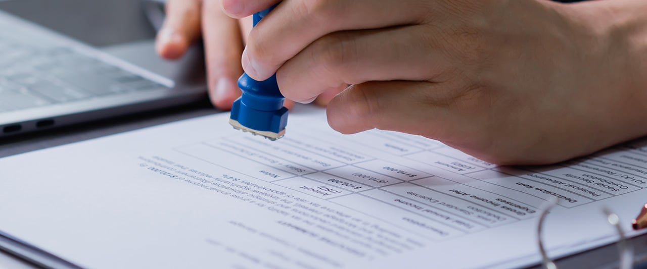 A male hand stamping approval on a document