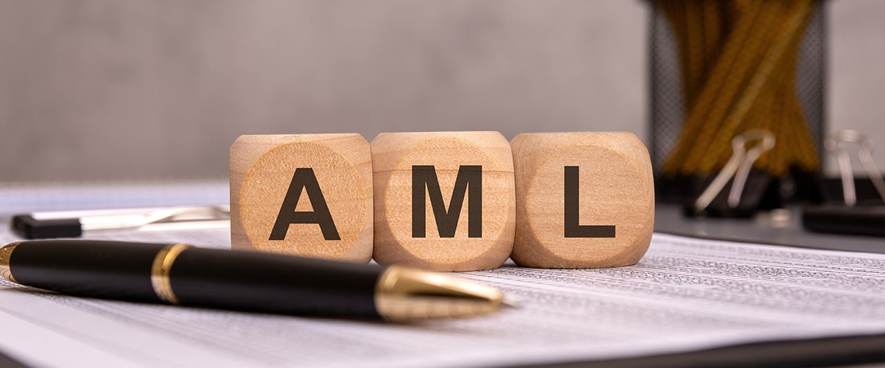 A pen resting on a document with block letters spelling out AML