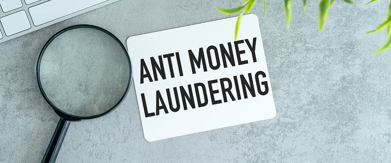 A magnifying glass on a desk next to a piece of paper saying 'Anti-Money-Laundering
