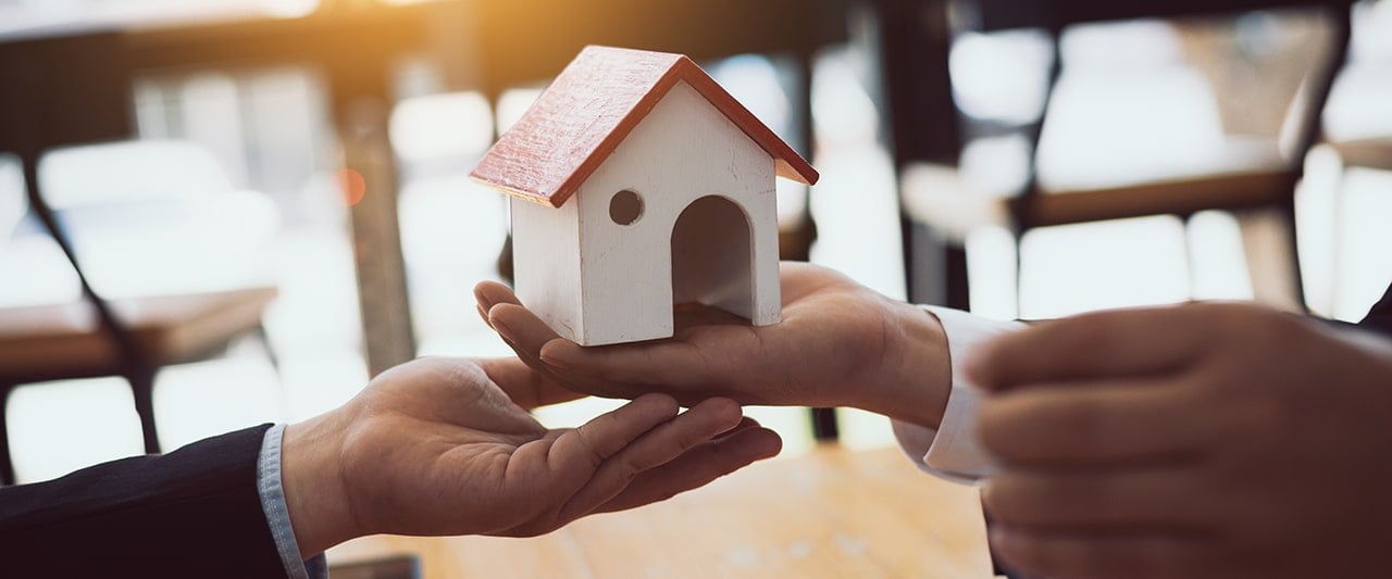 A decorative image depicting a model house changing hands