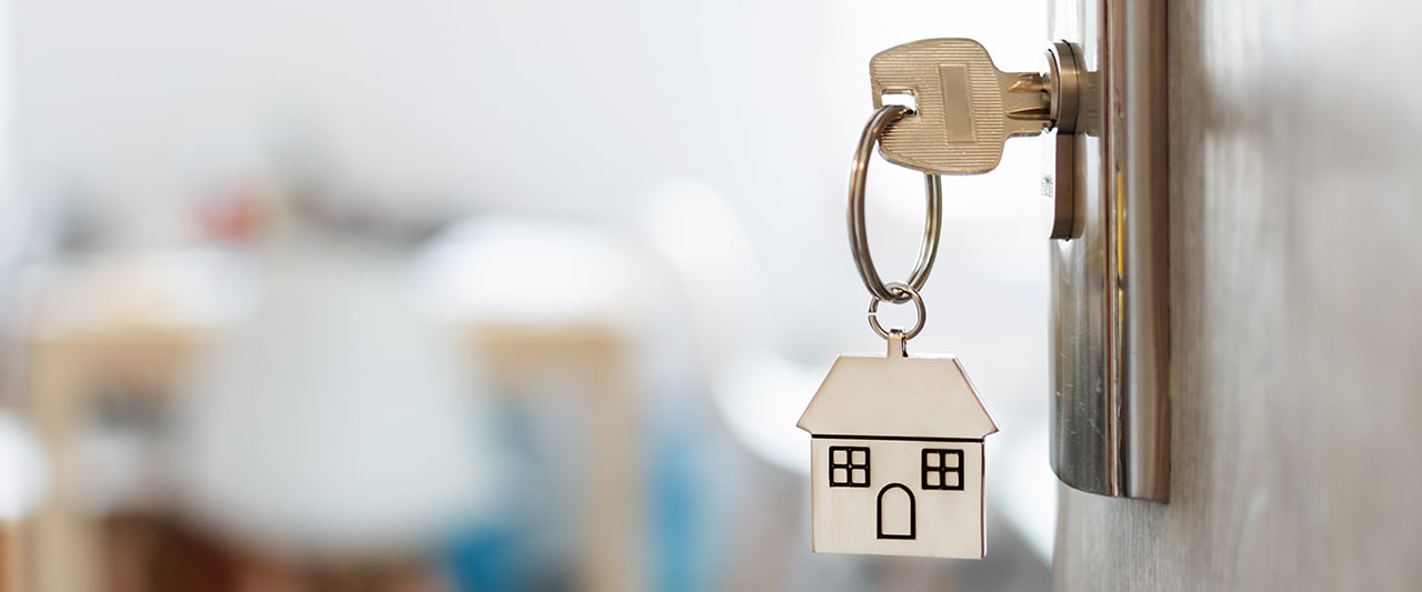 A decorative image of a key in a lock with a house-shaped keyring attached