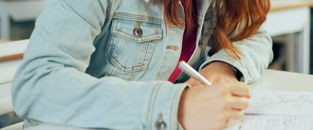 A student completing an exam with notebook and pen