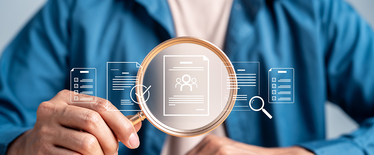 A person with a magnifying glass exploring candidate CVs for the CV register