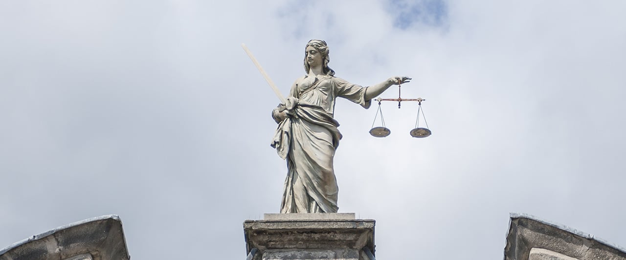 A stone statue of lady justice holding scales of justice
