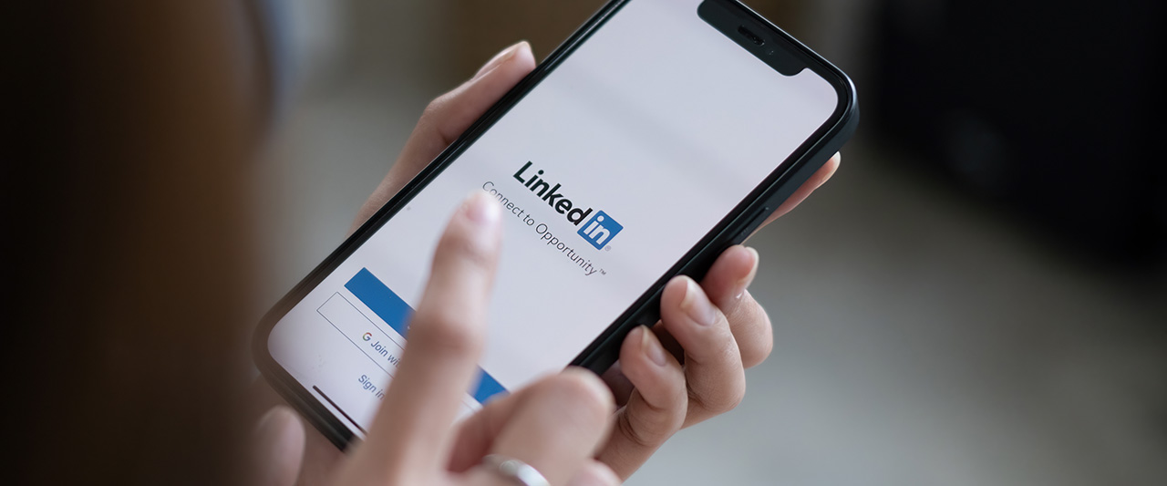 A female hand holding a phone and logging in to LinkedIn