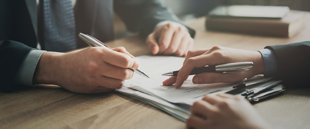 A person signing a document with help from a legal professional